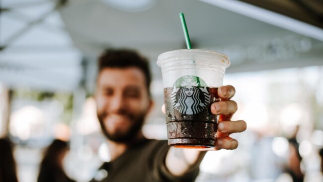 homme tenant une tasse starbucks